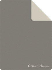 Graue Jacquard-Decke mit beiger Rückseite, perspektivisch von oben gezeigt, mit dem Schriftzug 'Gemütlichmacher' in der Ecke.