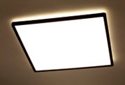 Quadratische LED-Deckenleuchte mit schwarzem Rahmen, von unten betrachtet, mit warmem Lichtschein an der Decke.