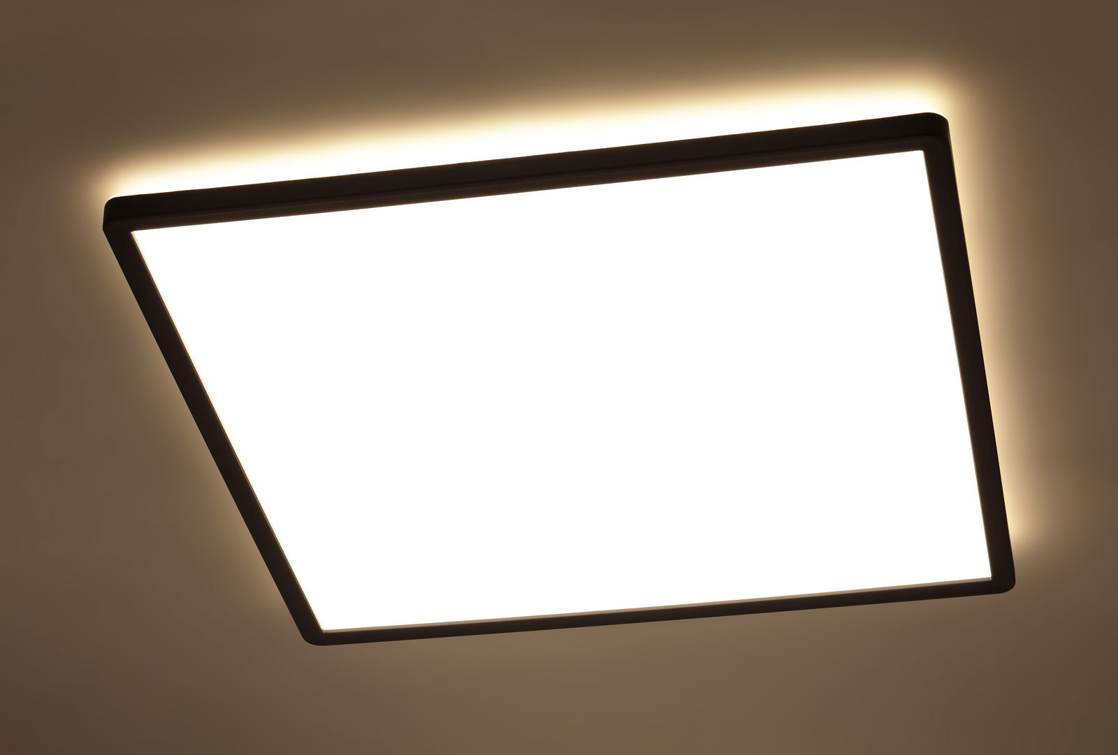 Quadratische LED-Deckenleuchte mit schwarzem Rahmen, von unten betrachtet, mit warmem Lichtschein an der Decke.