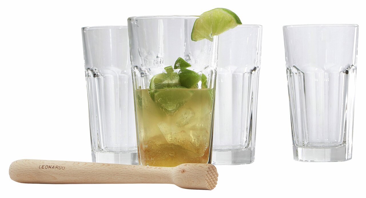Set aus vier klaren Gläsern und einem Holzstößel, frontal fotografiert, mit einem Glas gefüllt mit einem Getränk und Limettenscheiben.
