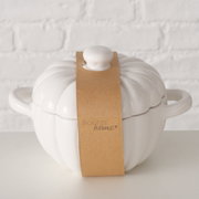 Witte, ronde ovenschaal met deksel en twee handvatten, gefotografeerd vanuit vooraanzicht, omwikkeld met bruin papierlint.