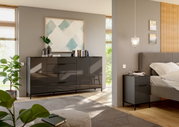 Modernes Schlafzimmer mit einem großen, glänzenden Sideboard und einer passenden Nachtkommode in dunklem Design, seitliche Perspektive.
