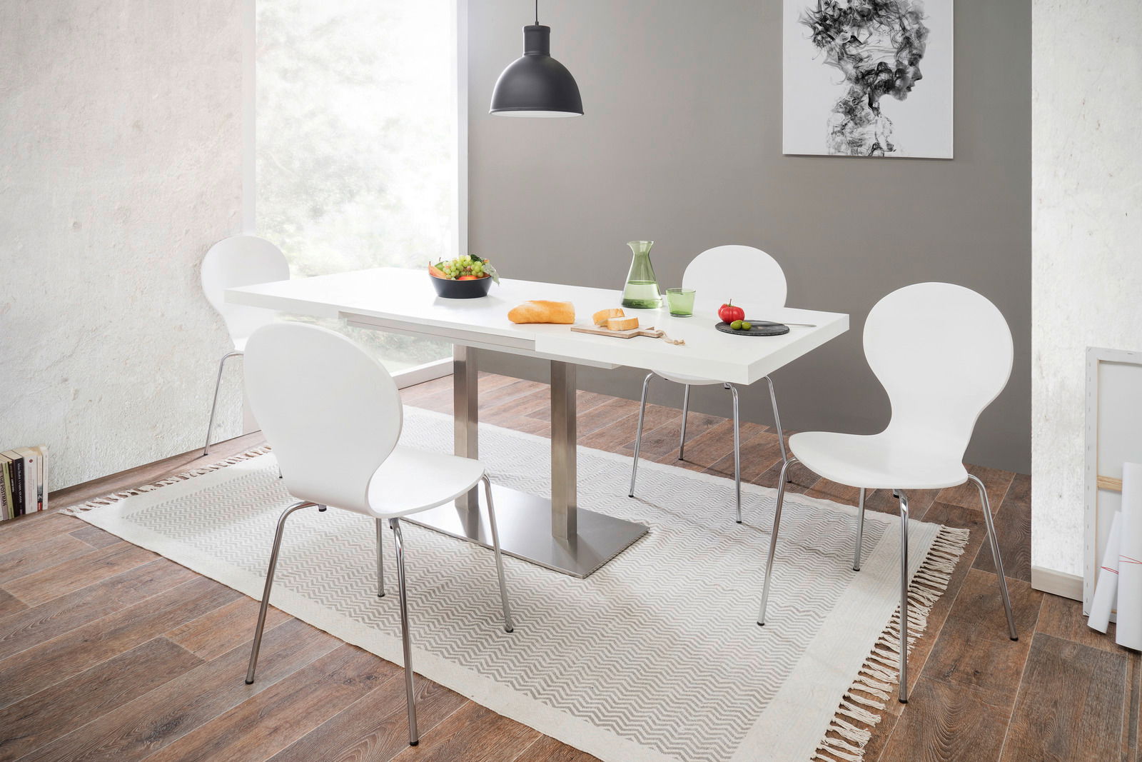 Moderner Esstisch mit weißer Tischplatte und Metallgestell, umgeben von vier weißen Stühlen in einem hellen Esszimmer mit Holzfußboden, aus seitlicher Perspektive fotografiert.