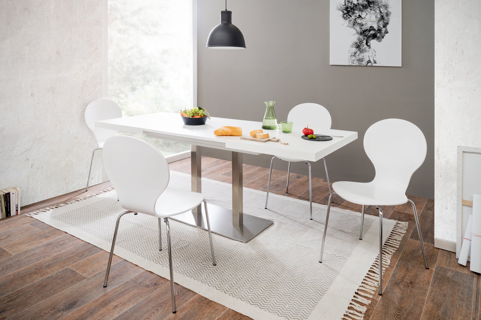 Moderner Esstisch mit weißer Tischplatte und Metallgestell, umgeben von vier weißen Stühlen in einem hellen Esszimmer mit Holzfußboden, aus seitlicher Perspektive fotografiert.