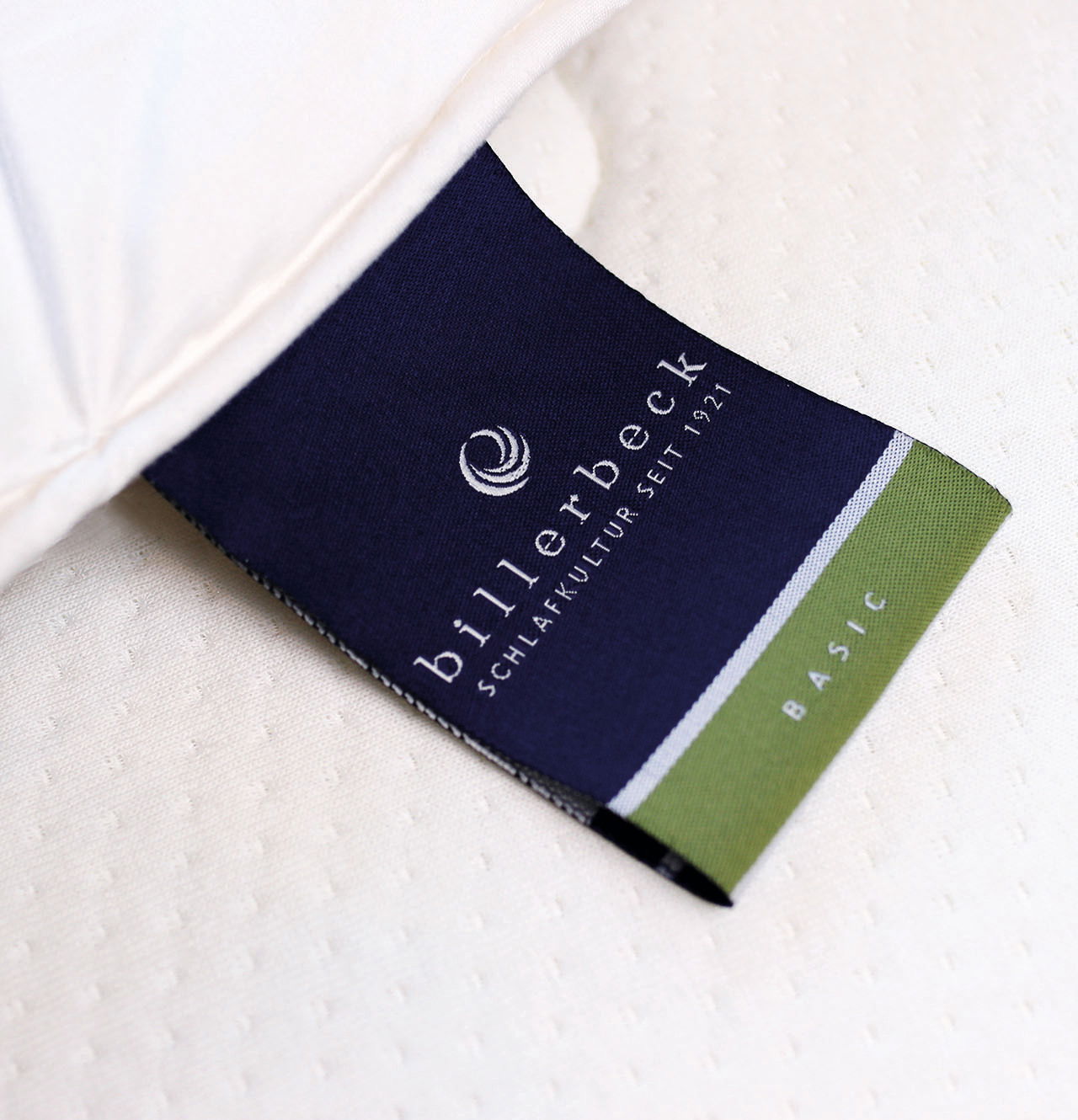 Nahaufnahme eines Etiketts der billerbeck Wildseidendecke Superlight Sari, das auf einem weißen Stoff liegt. Perspektive von oben.