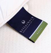 Nahaufnahme eines Etiketts der billerbeck Wildseidendecke Superlight Sari, das auf einem weißen Stoff liegt. Perspektive von oben.