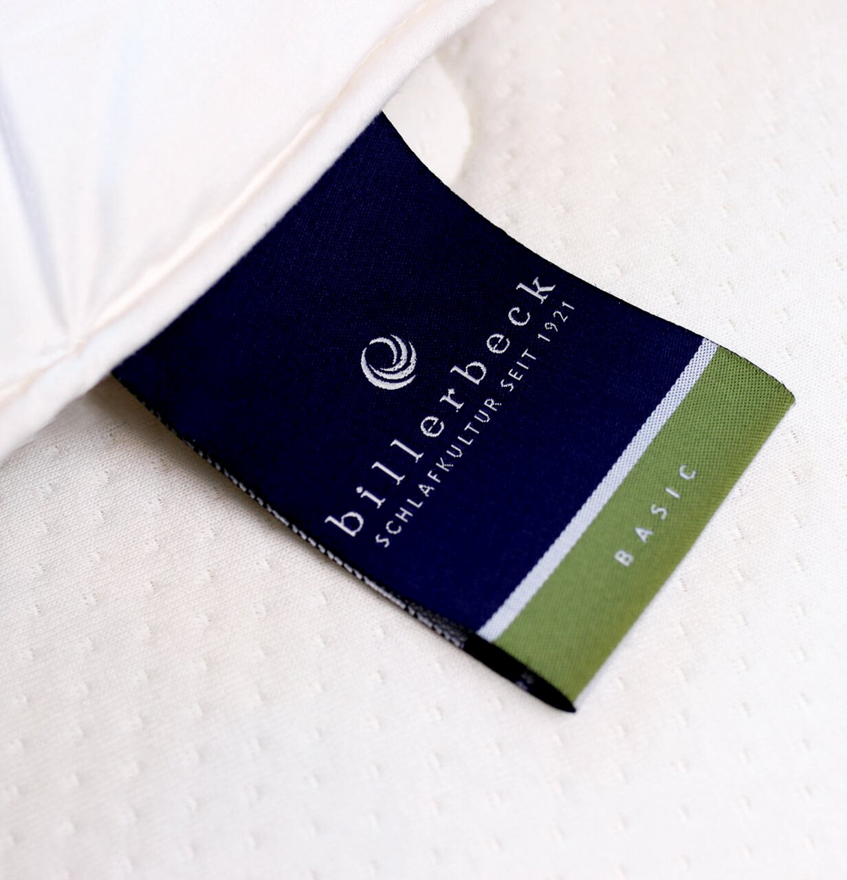 Nahaufnahme eines Etiketts der billerbeck Wildseidendecke Superlight Sari, das auf einem weißen Stoff liegt. Perspektive von oben.