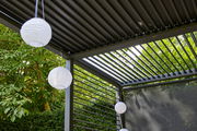 Pergola mit verstellbaren Lamellen und hängenden Papierlaternen, seitliche Perspektive