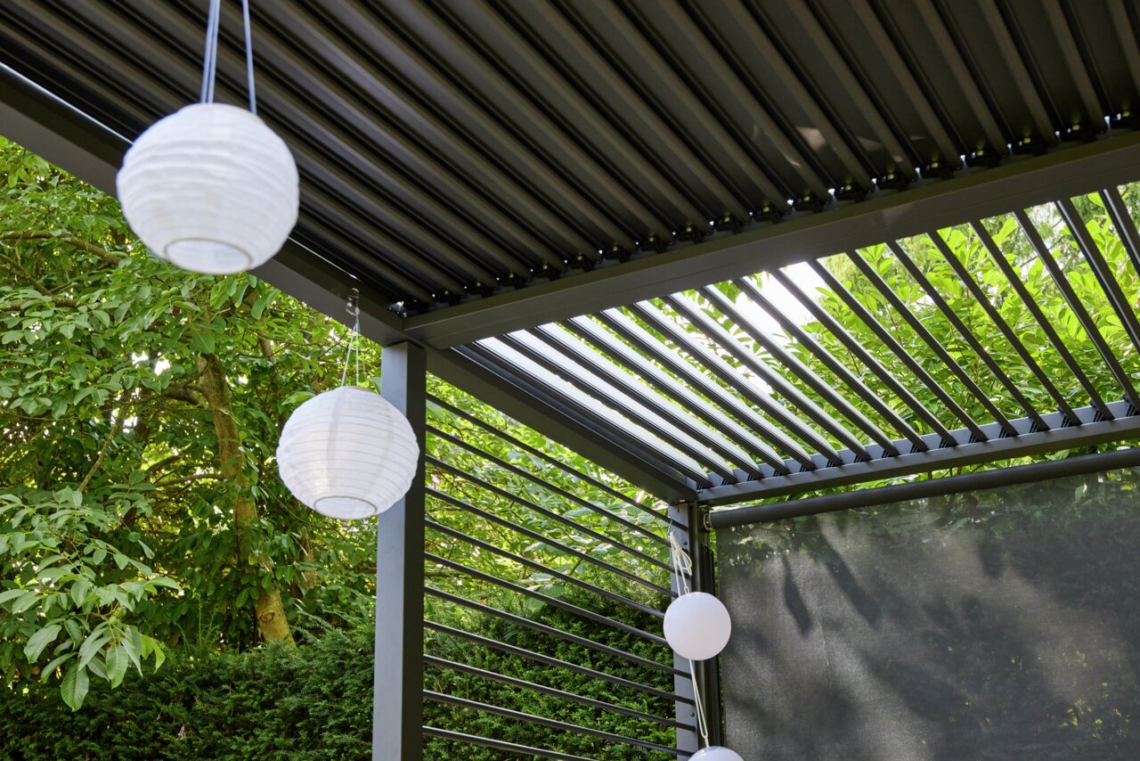 Pergola mit verstellbaren Lamellen und hängenden Papierlaternen, seitliche Perspektive