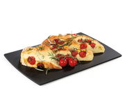 Schwarzes Schneidbrett mit Focaccia und frischen Tomaten, seitliche Perspektive