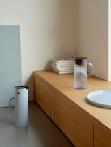 Stelton EM Kanne 1,5l in modernem Design, seitliche Perspektive auf einem Holztisch platziert.