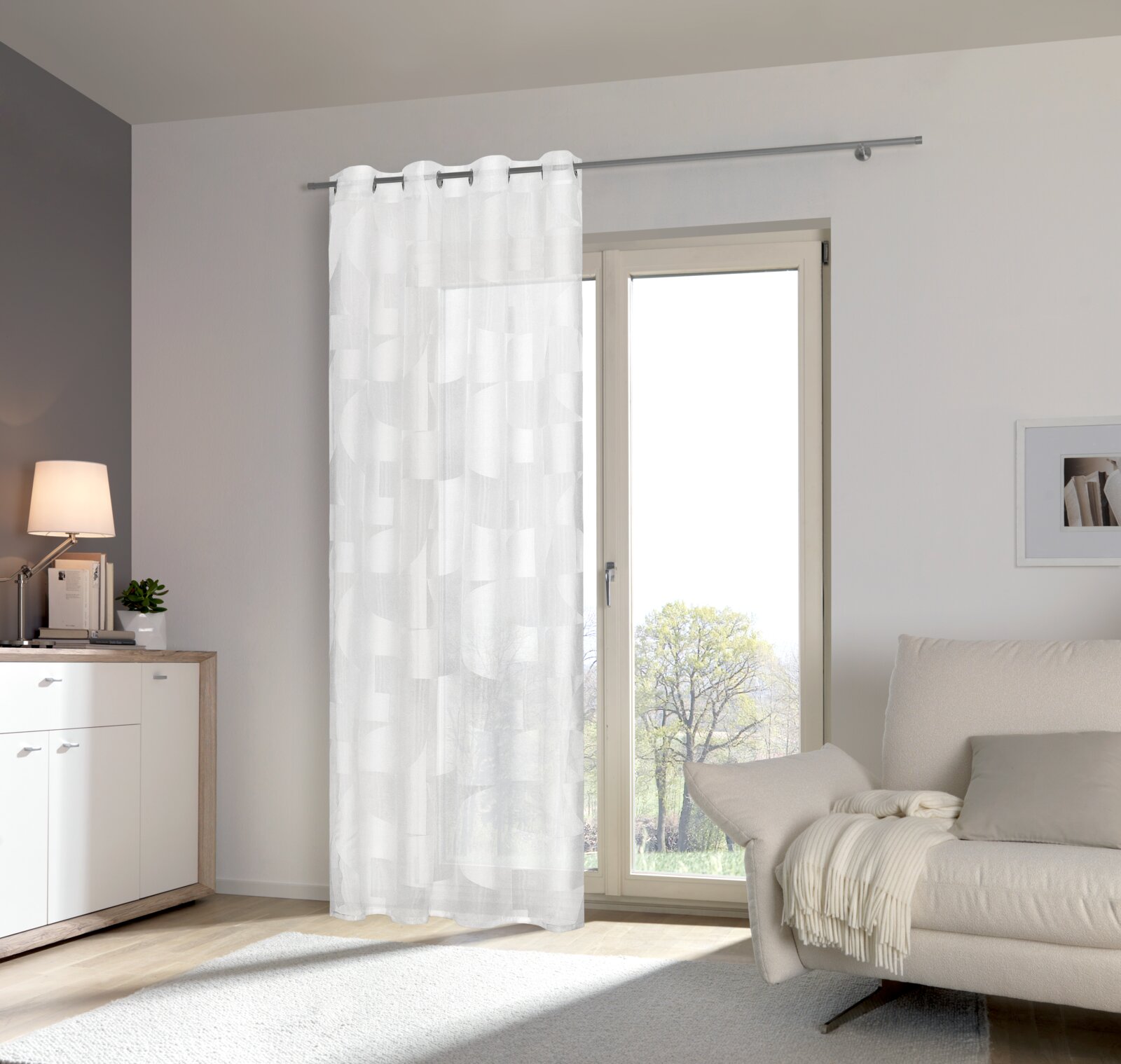 Moderner weißer Ösenschal vor einem Fenster in einem stilvoll eingerichteten Wohnzimmer, seitliche Perspektive.