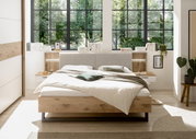 Modernes Schlafzimmer mit einem stilvollen Bett in Holzoptik, umgeben von großen Fenstern mit Blick ins Grüne. Frontalansicht.