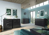 Modernes Wohnzimmer mit mehreren schwarzen Sideboards, darunter das XL-Sideboard Germania Sideboard OLEA, in einer stilvollen, hellen Umgebung mit großen Fenstern und dekorativen Elementen. Perspektive von vorne links.