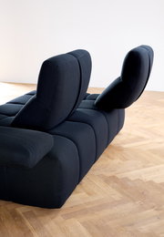 Rückansicht einer modernen, dunkelblauen Eckgarnitur mit verstellbaren Rückenlehnen auf einem Holzboden.