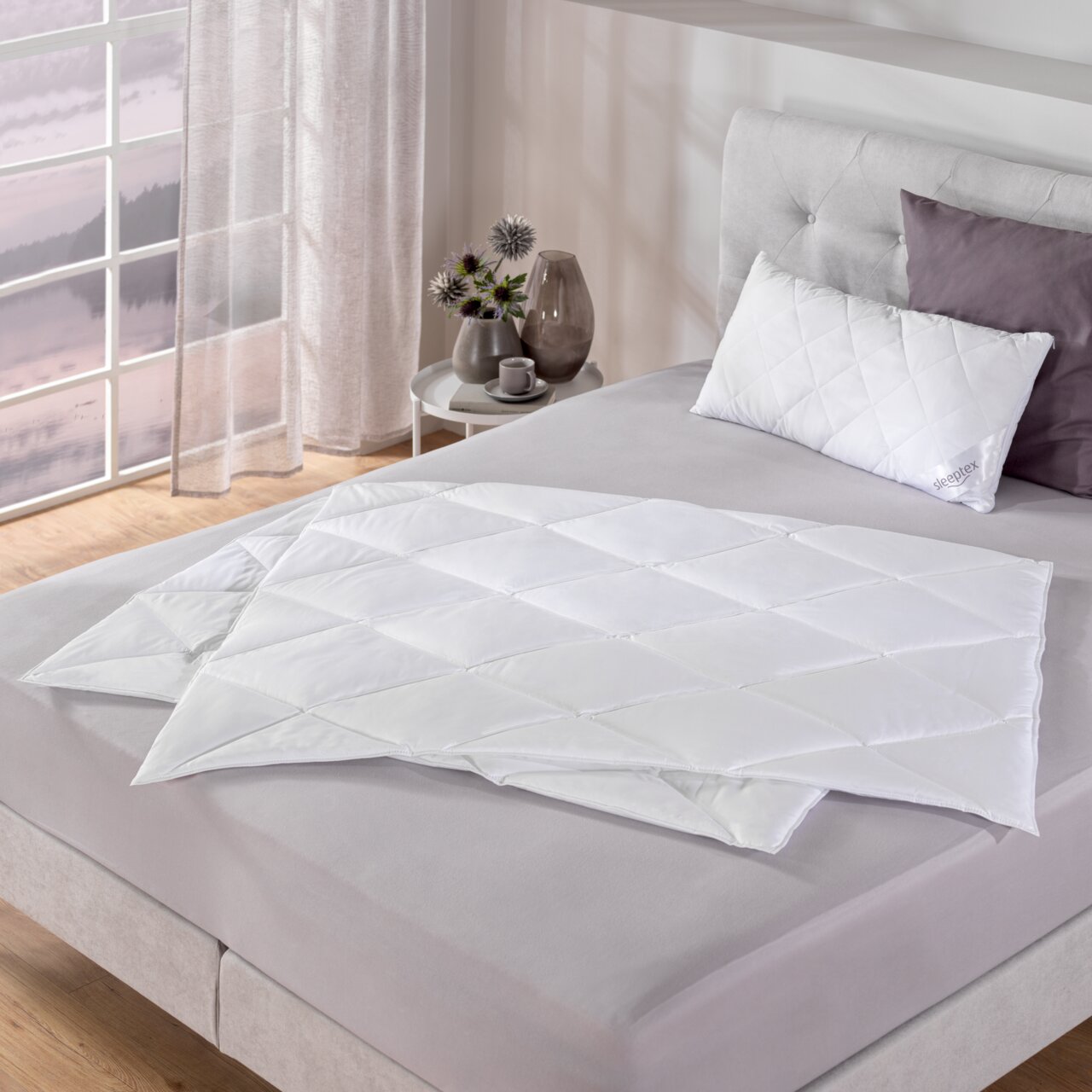 Sommerbettdecke 155x220 cm auf einem Bett, seitliche Perspektive, mit Kissen und Dekoration im Hintergrund.