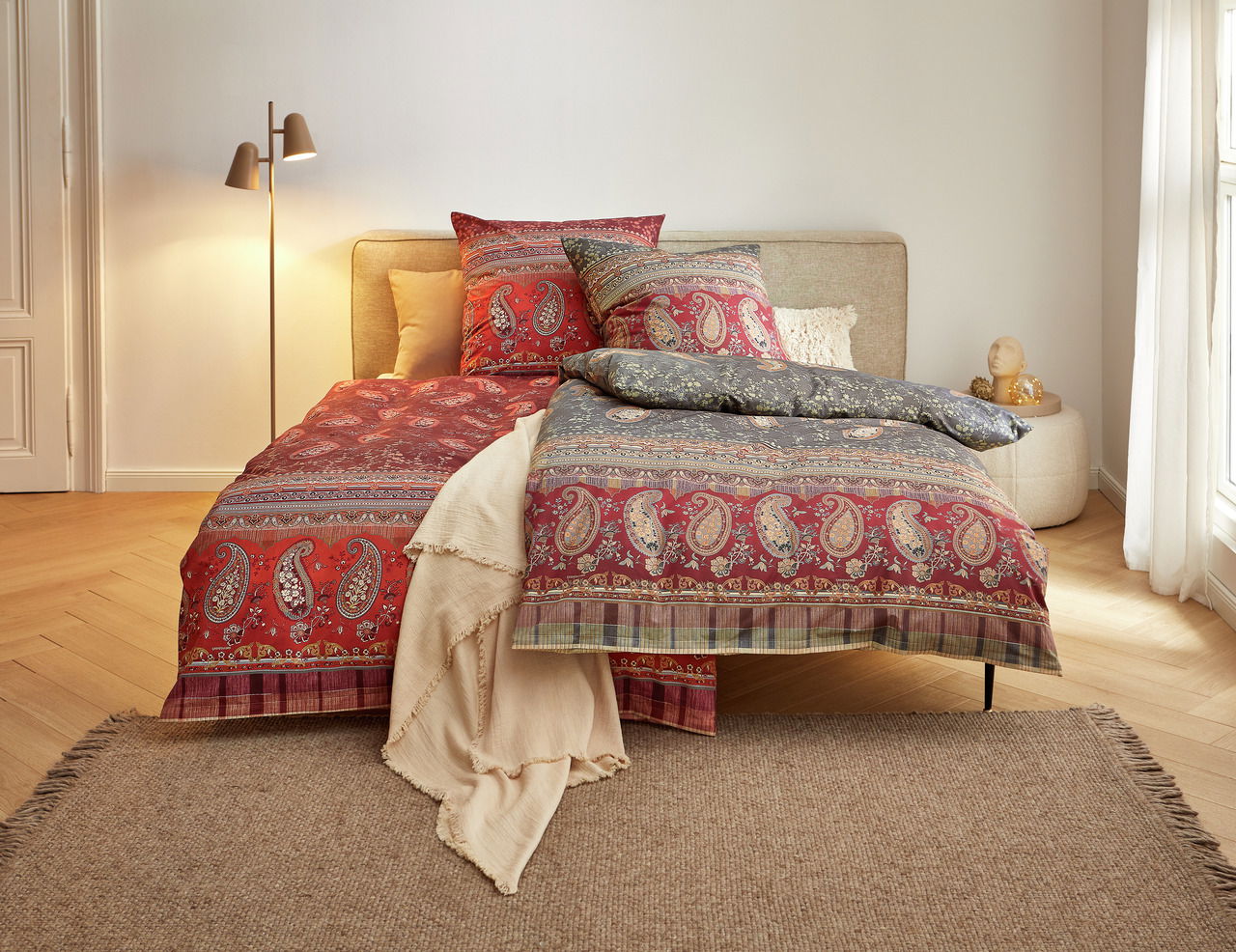 Bettwäsche-Set mit Paisley-Muster in Rot- und Grautönen auf einem Doppelbett, seitliche Perspektive