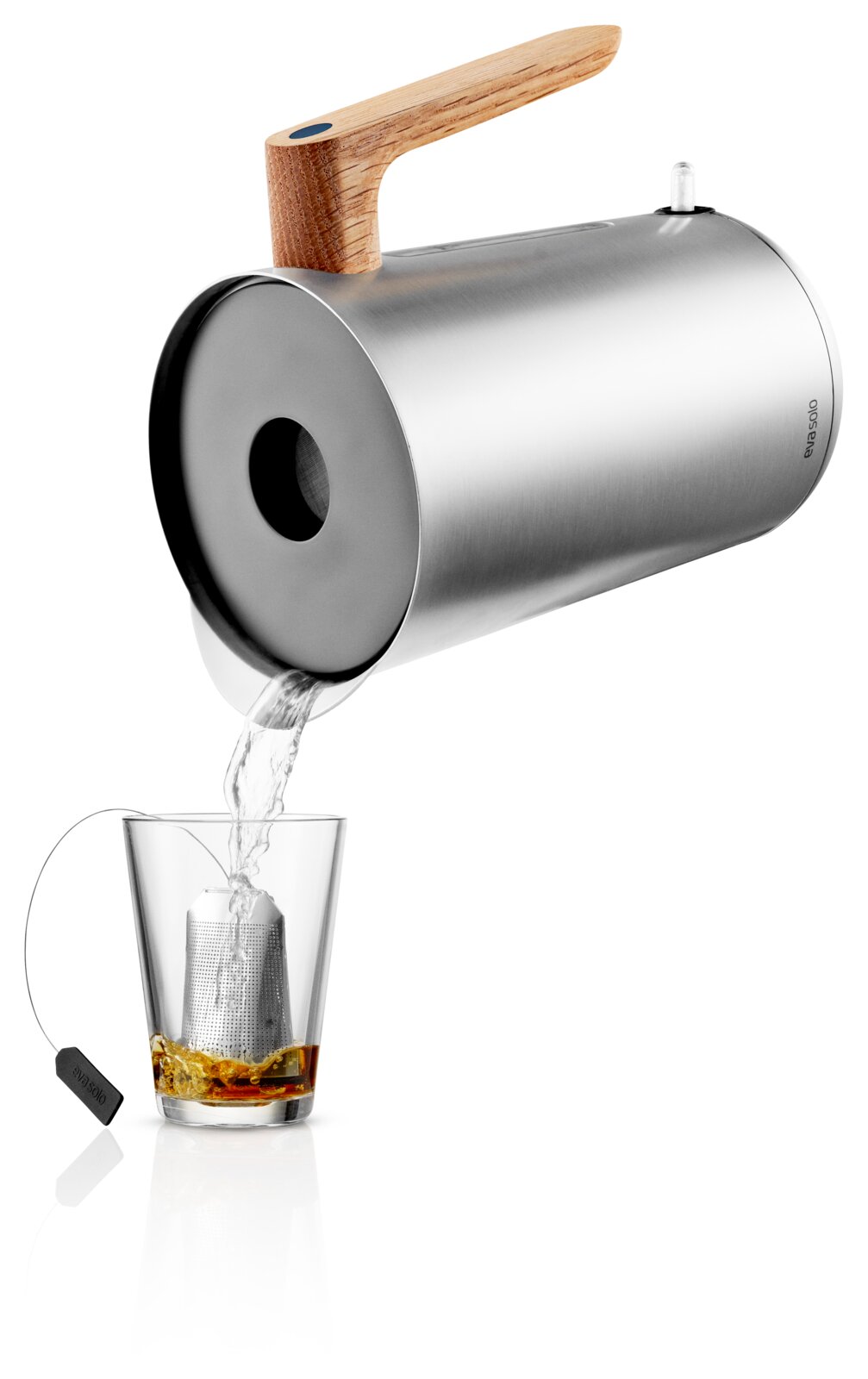 Roestvrijstalen theeketel met houten handgreep, schuin van voren gefotografeerd, giet heet water in een glas met metalen theefilter op witte achtergrond