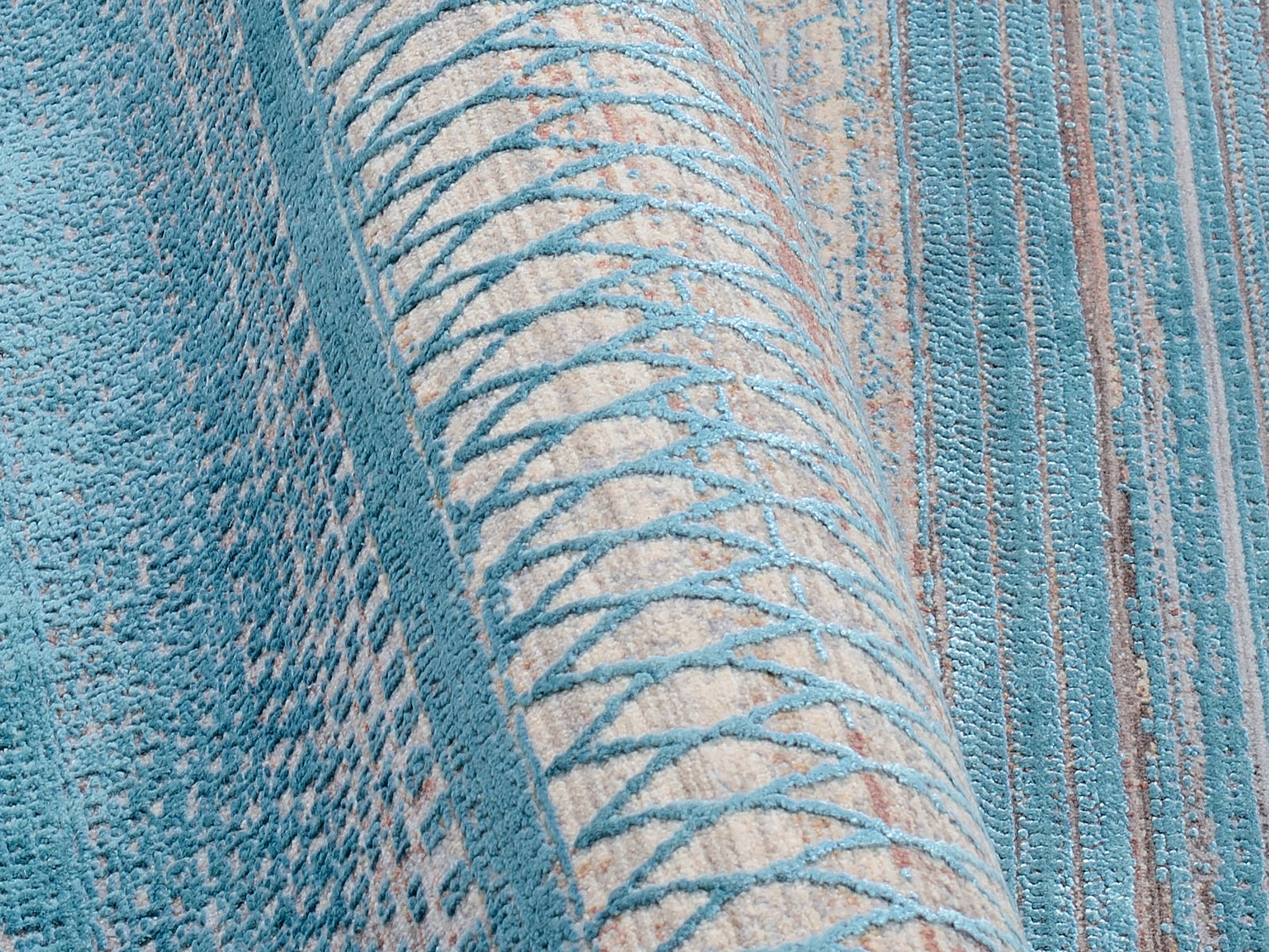 Nahaufnahme eines Designer-Teppichs in Blau- und Beigetönen mit geometrischem Muster, seitliche Perspektive