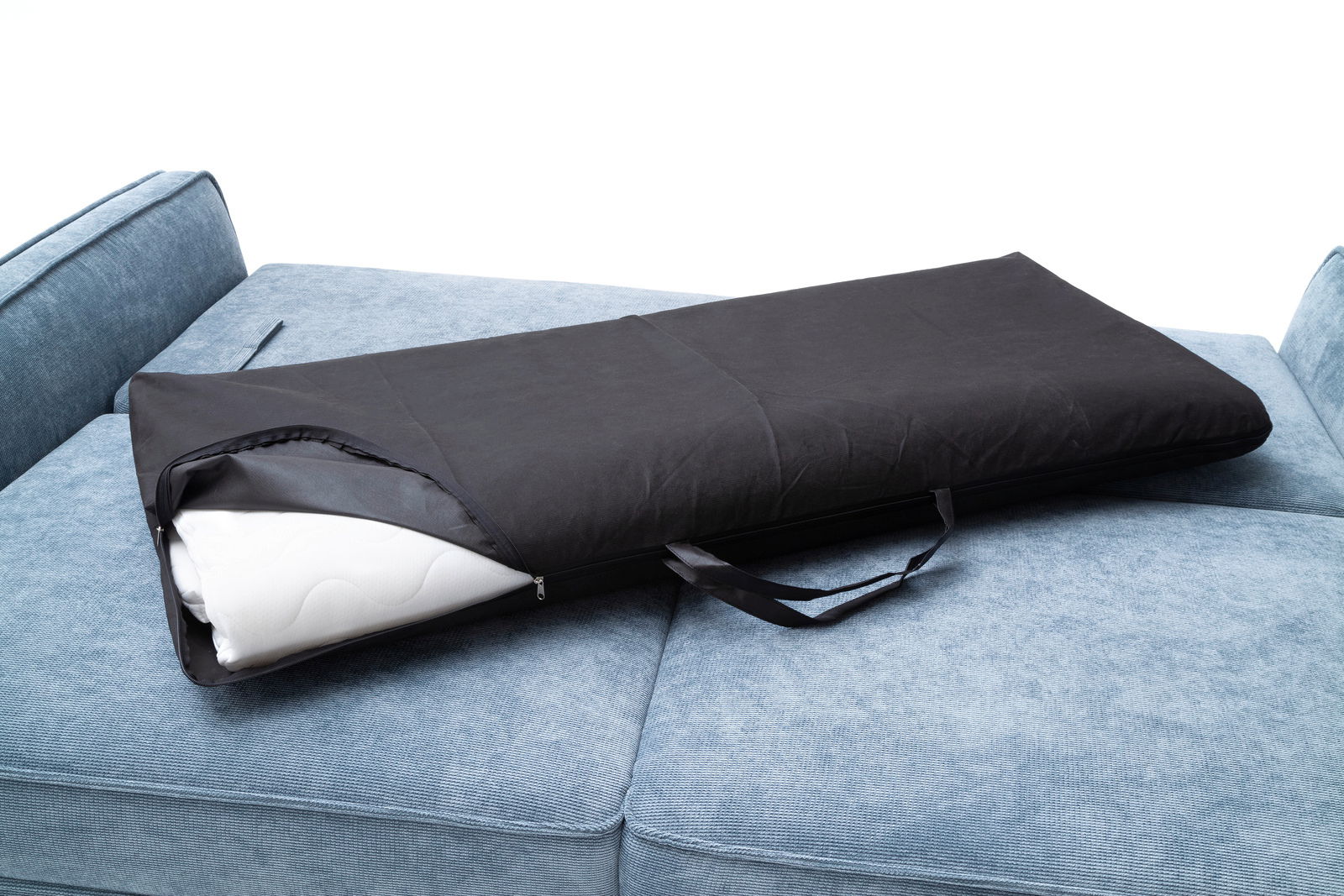 Schwarze Tragetasche mit Reißverschluss und Tragegriff auf einem blauen Funktionssofa, perspektivisch von oben fotografiert.