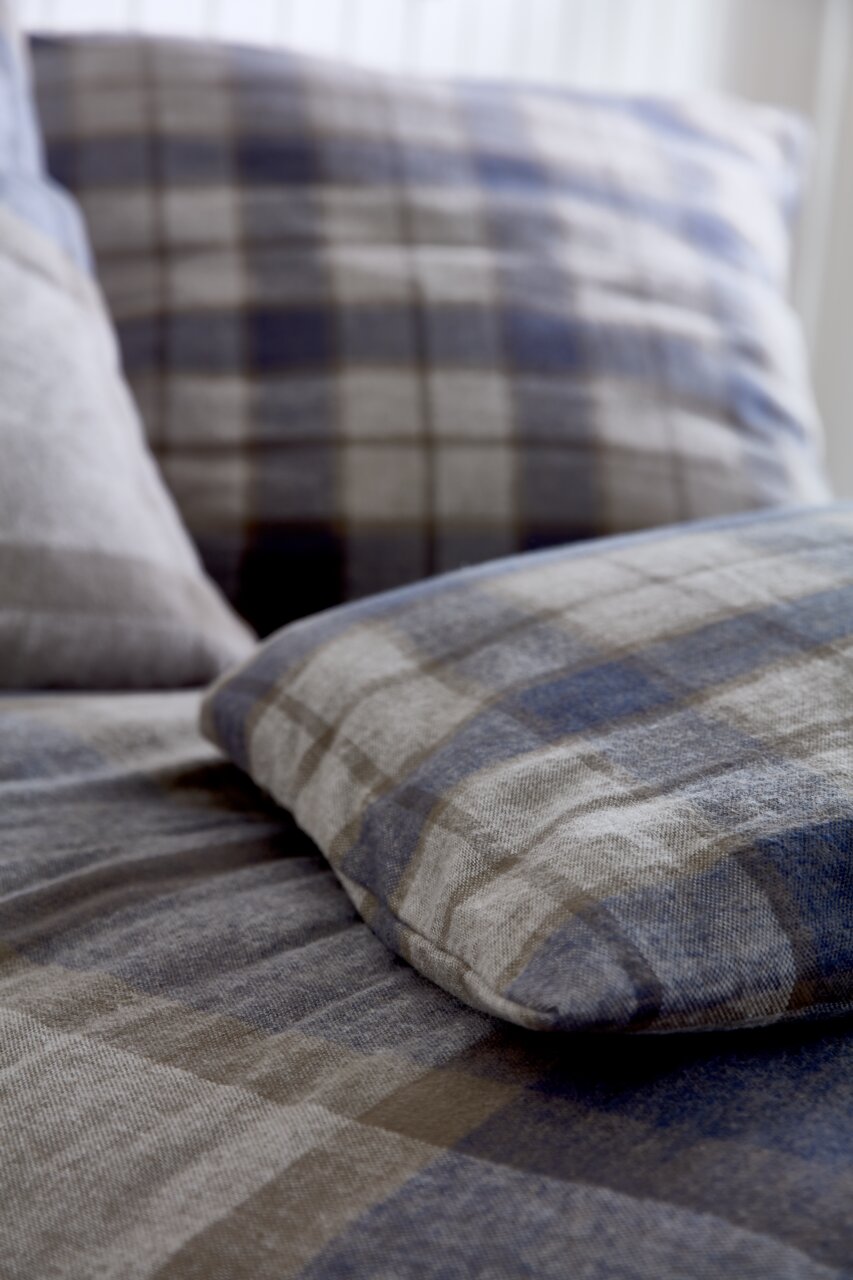 Nahaufnahme von kariertem Bettwäsche-Set in Blau- und Grautönen, Perspektive von der Seite