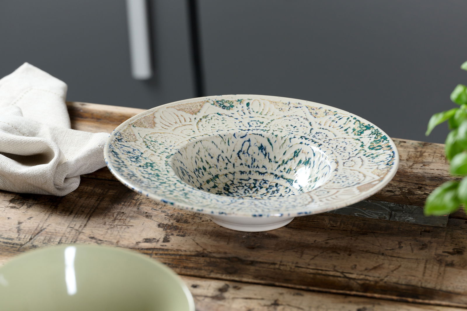 Ritzenhoff & Breker Gourmetteller LUIGI Gourmetteller 28 cm Luigi mit kunstvollem Muster, seitliche Perspektive auf einem Holztisch.