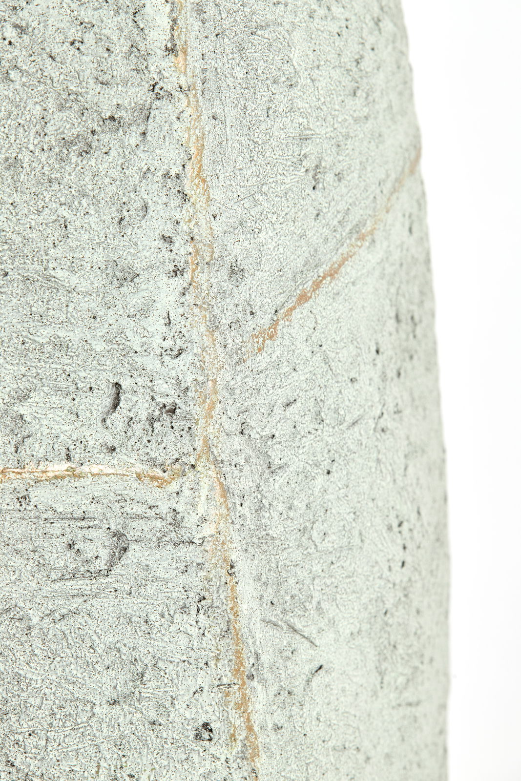 Nahaufnahme eines strukturierten, hellgrauen Topfes mit rauer Oberfläche und sichtbaren Nahtlinien.