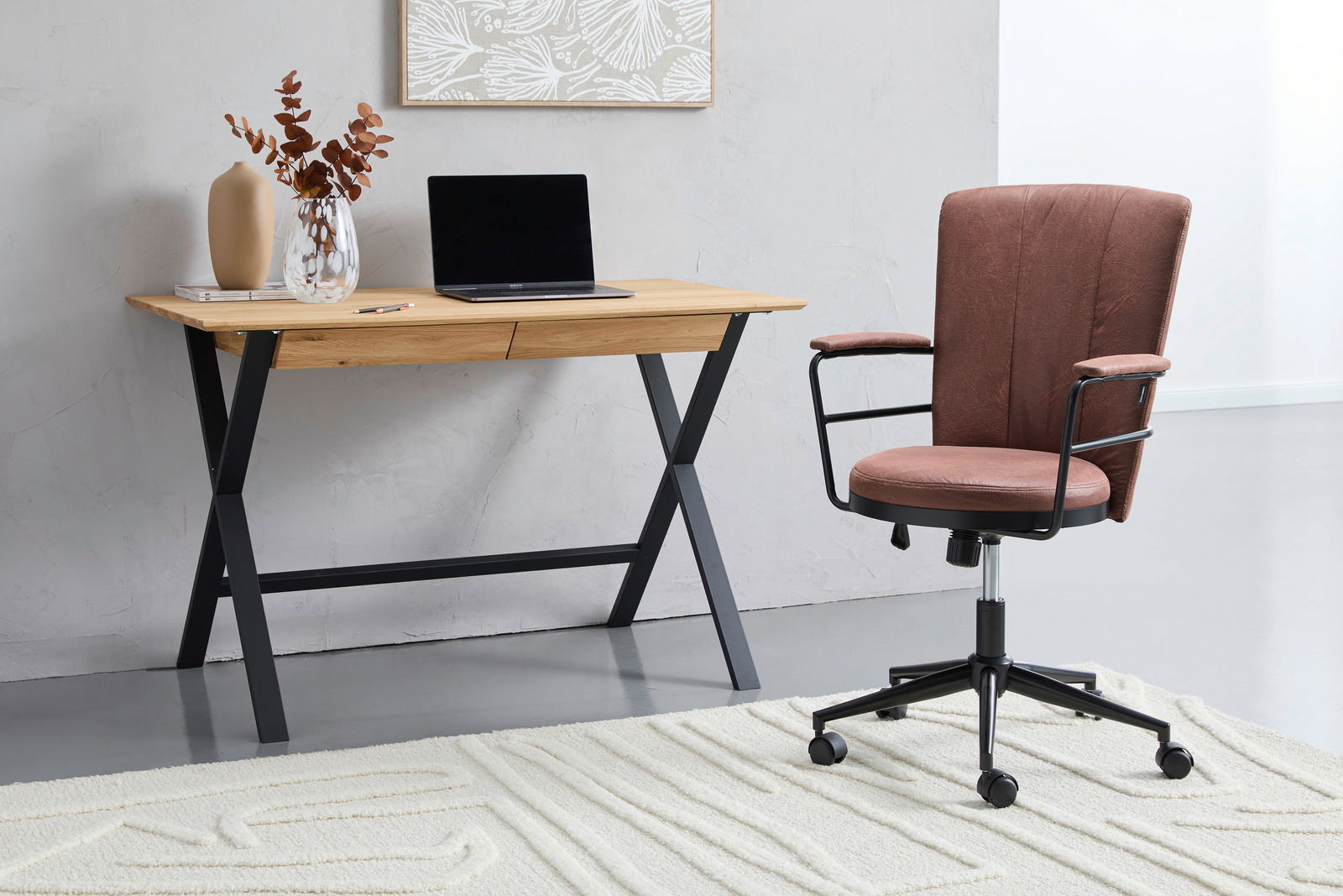 Moderner Schreibtisch mit Holzplatte und schwarzem Metallgestell, seitliche Perspektive, dekoriert mit Vase und Laptop, daneben ein gepolsterter Bürostuhl auf Teppich.