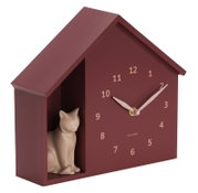 Wanduhr in Form eines Hauses mit einer kleinen Katzenfigur auf der linken Seite, seitliche Perspektive