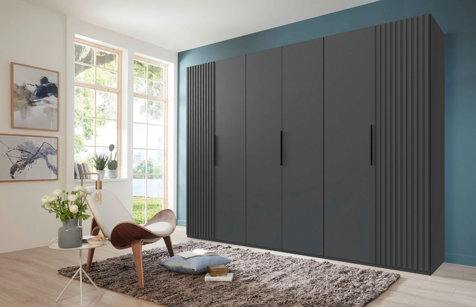 Moderner, sechstüriger Drehtürenschrank in dunklem Design, frontal fotografiert in einem stilvoll eingerichteten Raum mit großen Fenstern.