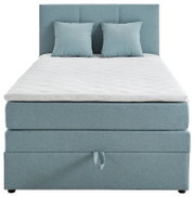 Boxspringbed met lichtblauwe bekleding en twee kussens, vooraanzicht