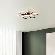 Moderne LED-Deckenleuchte in Blütenform mit fünf ovalen Leuchtringen in Schwarz/Weiß, warmweiß leuchtend, an weißer Zimmerdecke montiert, Perspektive von unten im Raum
