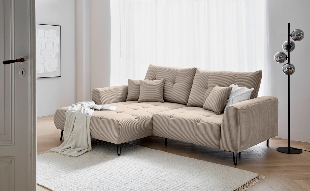 Z2 Ecksofa SWING Beige Ecksofa mit Ottomane links, dekoriert mit Kissen und Decke, in einem modernen Wohnzimmer mit hellem Holzboden und Stehlampe. Perspektive von der Seite.