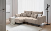 Beige hoekbank met poef aan de linkerkant, versierd met kussens en een deken, in een moderne woonkamer met een lichte houten vloer en een staande lamp. Aanzicht vanaf de zijkant.
