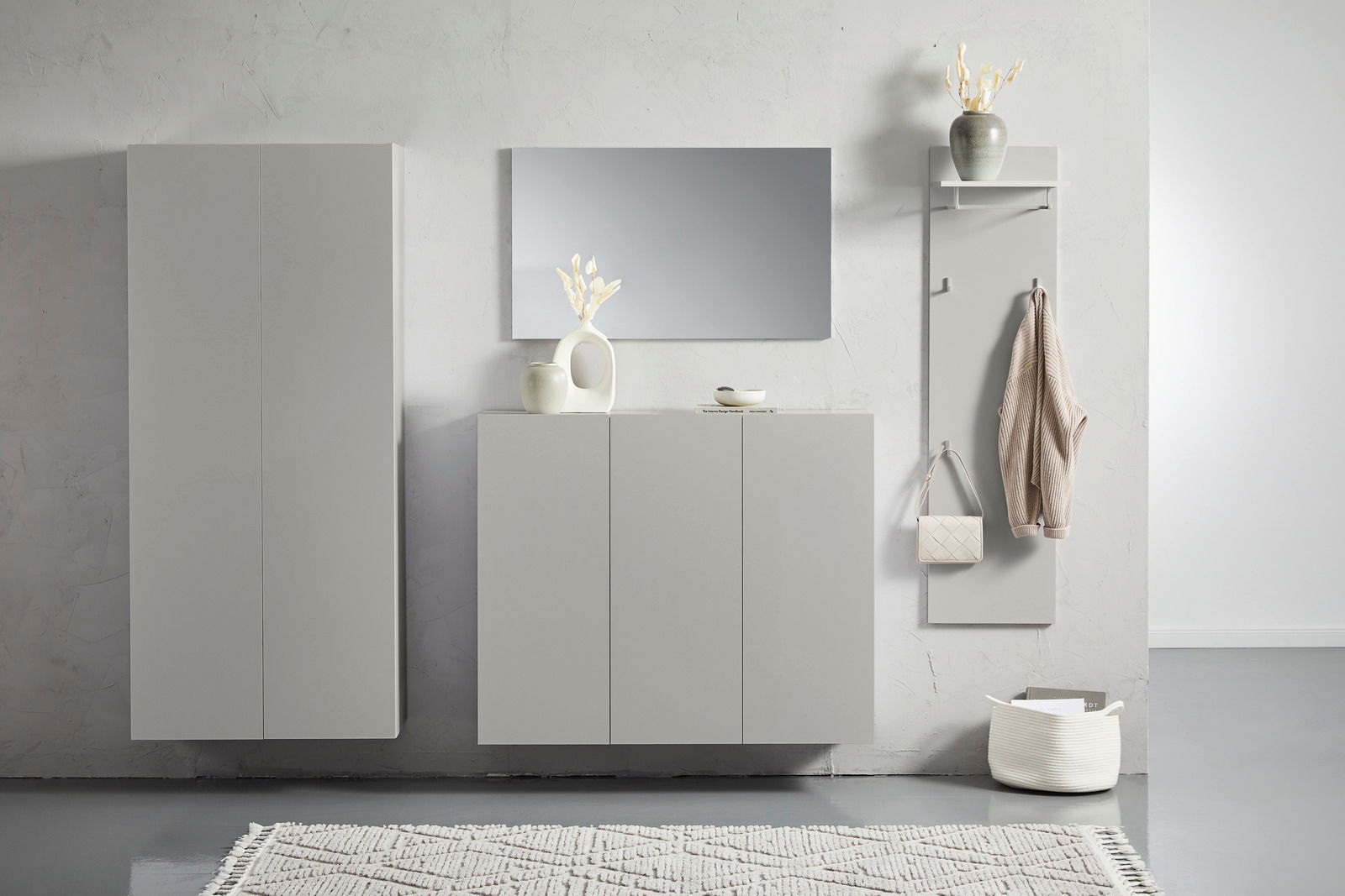 Moderner Hängeschuhschrank in hellem Grau, frontal fotografiert, mit dekorativen Elementen wie Vasen und Spiegel.