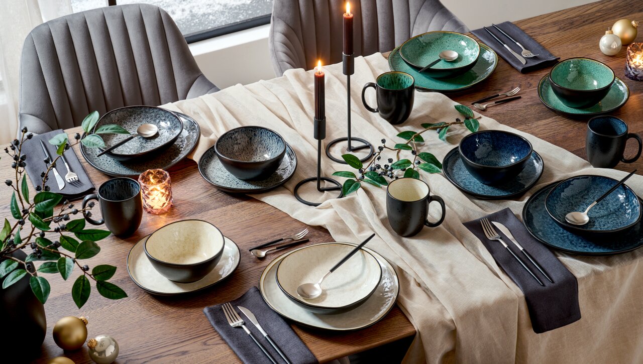 Elegantes Kombiservice für 10 Personen in verschiedenen Farben, auf einem festlich gedeckten Tisch mit Kerzen und Dekorationen, aus der Vogelperspektive fotografiert.