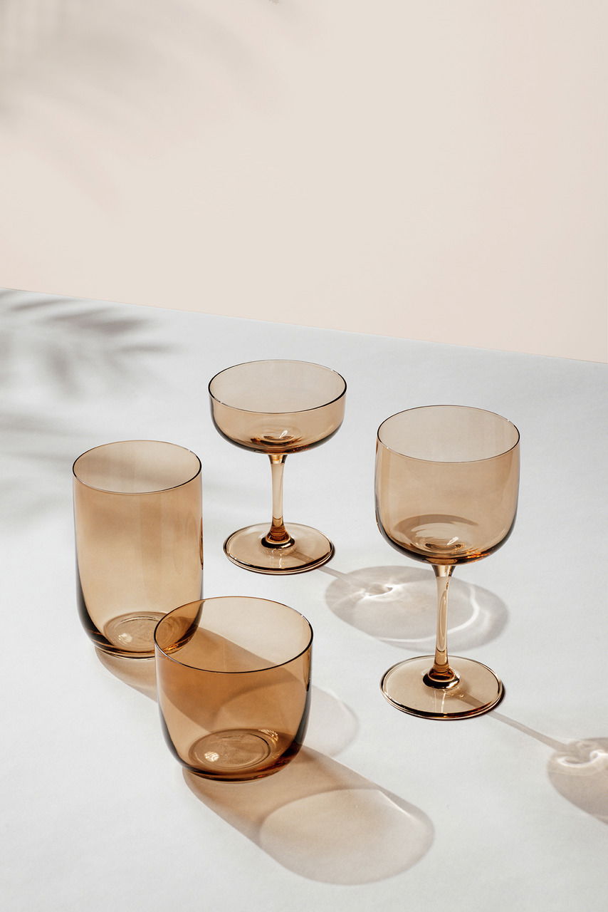 Set aus vier eleganten, rauchfarbenen Gläsern in verschiedenen Formen, auf einer hellen Oberfläche aus der Vogelperspektive fotografiert.