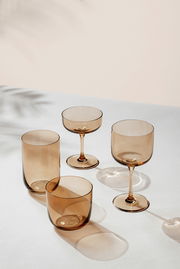 Set aus vier eleganten, rauchfarbenen Gläsern in verschiedenen Formen, auf einer hellen Oberfläche aus der Vogelperspektive fotografiert.