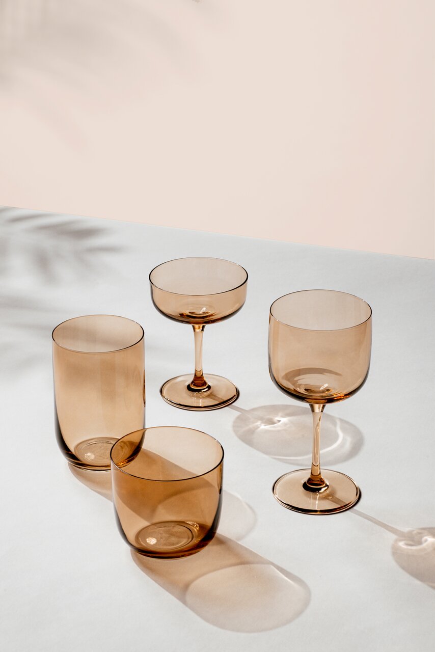 Set aus vier eleganten, rauchfarbenen Gläsern in verschiedenen Formen, auf einer hellen Oberfläche aus der Vogelperspektive fotografiert.