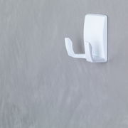 Weiße Wandhakenhalterung, seitliche Perspektive, an einer grauen Wand montiert.