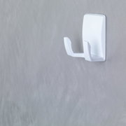 Weiße Wandhakenhalterung, seitliche Perspektive, an einer grauen Wand montiert.
