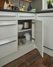 Eckunterschrank in einer modernen Küche, geöffnet, mit Töpfen und Schüsseln auf zwei Regalböden, aus der Perspektive von vorne rechts.