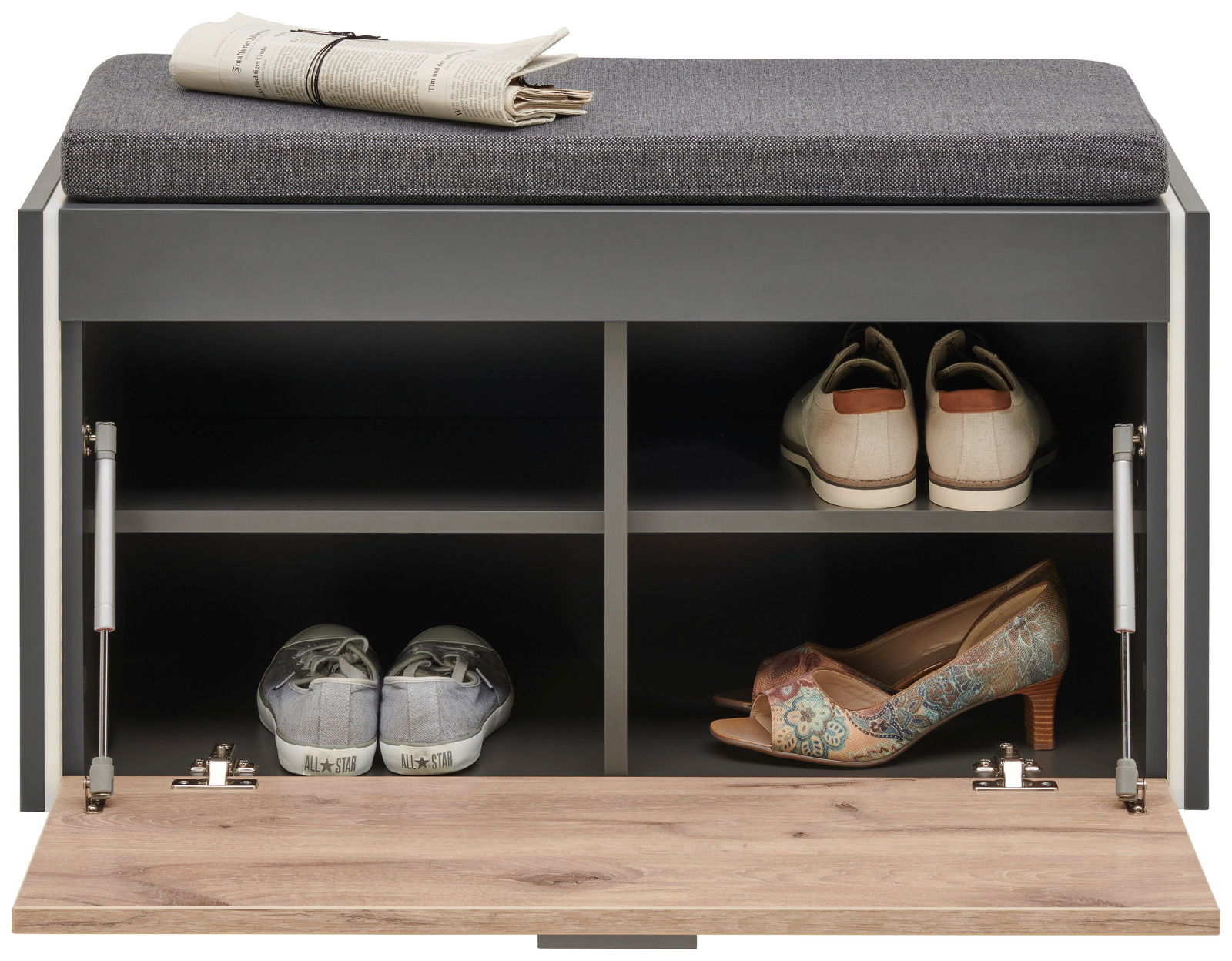 Garderobenbank mit grauem Polster, von vorne gesehen, mit offenen Fächern, die Schuhe und eine Zeitung auf der Sitzfläche zeigen.