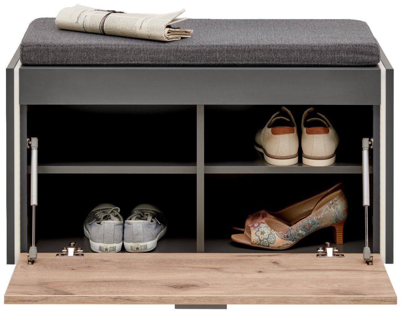 Garderobenbank mit grauem Polster, von vorne gesehen, mit offenen Fächern, die Schuhe und eine Zeitung auf der Sitzfläche zeigen.