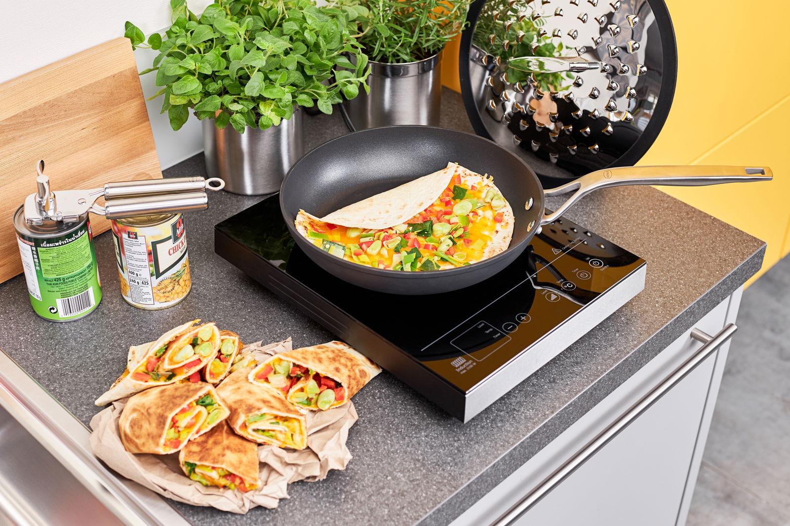 Bratpfanne Raise Ø 20 cm auf einem Induktionskochfeld, gefüllt mit einem bunten Omelett, umgeben von frischen Kräutern und Zutaten, von oben fotografiert.