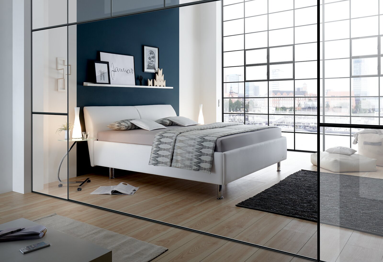 Modernes Polsterbettgestell in einem stilvollen Schlafzimmer mit großen Fenstern und Holzboden, seitliche Perspektive