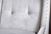 Nahaufnahme eines grauen, gepolsterten Stuhls mit Knopfdetails und seitlicher Perspektive.