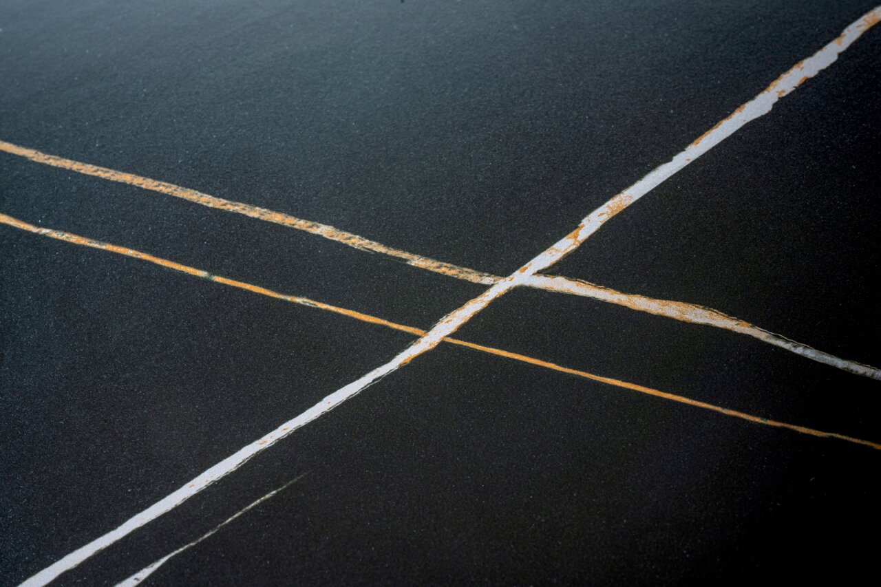 Nahaufnahme einer Tischplatte mit dunkler Oberfläche und hellen, diagonalen Linien.