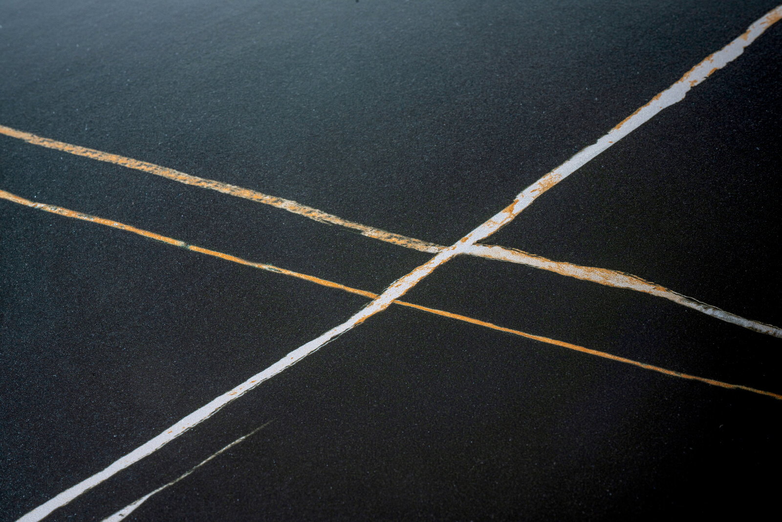 Nahaufnahme einer Tischplatte mit dunkler Oberfläche und hellen, diagonalen Linien.