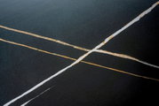 Nahaufnahme einer Tischplatte mit dunkler Oberfläche und hellen, diagonalen Linien.